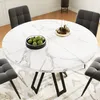 A round marble-look dining table with dark metal legs, surrounded by four dark gray chairs. A bowl of green fruit and a decorative tray with bottles are on the table. Produktbild-Vorschau