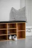 A shoe storage bench with a cushion and a pillow, placed against a wall with a radiator. Náhled obrázku produktu