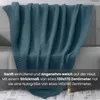 A teal knitted blanket draped over a sofa. Náhled obrázku produktu