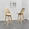 Two beige bar stools with wooden legs are shown in front of a white brick wall. Náhľad obrázku produktu