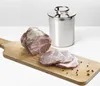 A piece of cooked meat and slices of meat are displayed on a wooden cutting board next to a stainless steel cooking pot. Podgląd zdjęcia produktu