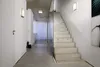 A modern interior hallway with a concrete floor and ceiling, a glass partition, and a concrete staircase. Produktbild-Vorschau