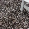 A close-up view of a shaggy rug with a white stool leg in the corner. Podgląd zdjęcia produktu