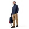 Mann mit grauen Haaren trägt einen blauen Berghaus Prism Half-Zip Polartec-Fleece und beige Hose; hält einen Rucksack. Produktbild-Vorschau