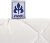 A close-up of a white quilted pillow with a brand tag attached. Produktbild-Vorschau
