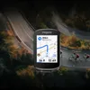 A GPS cycling computer is shown in the foreground, with cyclists riding on a winding road in the background. Produktbild-Vorschau