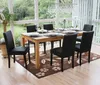 A dining room with a wooden table and chairs set up for a meal, with large windows overlooking a garden. Podgląd zdjęcia produktu