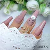 A close-up shot of a hand with long, pink, coffin-shaped nails, adorned with a ring featuring a crescent moon and star. One nail has a cartoon face design. Anteprima dell’immagine prodotto