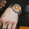 A close-up shot of a person's wrist wearing a silver and orange Casio G-Shock watch. Produktbild-Vorschau
