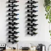 Two black metal wine racks mounted on a white wall, each holding multiple wine bottles. The racks are positioned above a kitchen counter with some appliances and containers. Produktbild-Vorschau