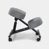 A gray ergonomic kneeling chair with a black metal frame and wheels, shown from the side against a plain light gray background. Produktbild-Vorschau