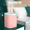 A pink humidifier is placed on a teal table next to a bed with white pillows and a green pillow. Náhľad obrázku produktu
