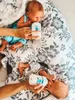 Two babies being fed with bottles on a floral patterned pillow. Voir les images du produit