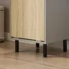 A close-up view of the bottom section of a cabinet with a wood-grain door and gray side panel, resting on black legs. Produktbild-Vorschau