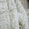 A close-up view of a soft, textured beige blanket. Produktbild-Vorschau