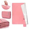 A pink picnic blanket is shown in various folded and unfolded states, with a hand holding its handle. Podgląd zdjęcia produktu