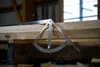 A metal angle measuring tool is placed on wooden planks in a workshop setting. Anteprima dell’immagine prodotto