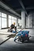 A construction worker is using a concrete saw connected to a vacuum cleaner to cut grooves in a concrete floor. Anteprima dell’immagine prodotto
