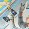 A person is using a Bosch cordless impact driver to screw a metal strip onto wooden beams in what appears to be a construction or renovation setting. Produktbild-Vorschau