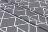 A close-up view of a folded grey fabric with a white geometric pattern. Produktbild-Vorschau