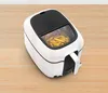 A white and black air fryer filled with french fries, placed on a wooden surface. Produktbild-Vorschau
