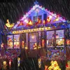 A house decorated with numerous Christmas lights and figures during a rain shower. Produktbild-Vorschau