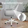 A gray velvet office chair with a headrest and lumbar support illustration, set in a home office environment with a desk and window in the background. Produktbild-Vorschau