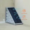 Graue dreieckige Solar-Wandleuchte mit mehreren LED-Lampen und einem Solarmodul, montiert an einer hellen Wand Náhľad obrázku produktu