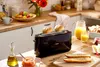 A breakfast scene with a toaster, bread, orange juice, and fruit. Produktbild-Vorschau