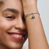 A close-up shot of a woman's arm wearing a Pandora bracelet with an avocado charm. Voir les images du produit