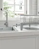 A kitchen sink area with a faucet running water into the sink and a dish rack on the counter. Náhled obrázku produktu
