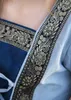 Close-up of a blue dress with gold and black trim. Produktbild-Vorschau