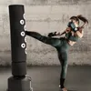 A woman is kicking a black punching bag in a gym. Produktbild-Vorschau
