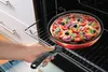 A hand is placing a pizza in a pan into an oven. Podgląd zdjęcia produktu