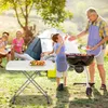 A family is enjoying a barbecue in a park, with a portable table in the foreground. Produktbild-Vorschau