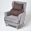 A grey armchair with a brown lumbar pillow on it, set against a white background. Náhled obrázku produktu