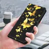 A hand holding a black phone case with a gold butterfly design. Produktbild-Vorschau