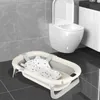 A baby bathtub is placed on the floor in front of a toilet in a bathroom. Produktbild-Vorschau