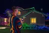 A man is holding a smartphone and looking at a house decorated with colorful LED lights. Podgląd zdjęcia produktu