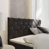 A close-up view of a tufted headboard of a bed with crystal accents, with pillows and bedding visible. Produktbild-Vorschau