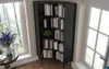 A black corner bookshelf filled with books is placed next to a window with a view of trees. A round table with a vase of flowers is in the foreground. Produktbild-Vorschau