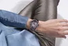 A person wearing a watch on their wrist, showing the watch face and band. Náhľad obrázku produktu