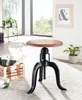 A wooden and black metal adjustable stool is shown in a bright, airy room with large windows and plants. Produktbild-Vorschau