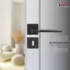 A black door handle and lock set on a white door, with a blurred background of a room interior. Produktbild-Vorschau