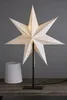 A white star-shaped lamp shade is displayed on a wooden table. Podgląd zdjęcia produktu