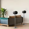 Two black speakers on stands in a living room next to a sofa. Produktbild-Vorschau