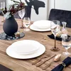A dining table setting with plates, glasses, cutlery, and a vase of flowers. Podgląd zdjęcia produktu