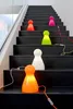 Several colorful, pawn-shaped lamps are placed on the steps of a modern staircase. Produktbild-Vorschau
