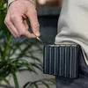 A person is holding a coin over a black coin dispenser attached to their waist. Podgląd zdjęcia produktu