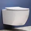 A white wall-mounted toilet with a closed lid is shown against a blue wall and a speckled gray floor. Náhled obrázku produktu